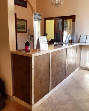 Un comptoir d’accueil avec une pancarte, une bouteille et un tableau encadré accroché au mur.