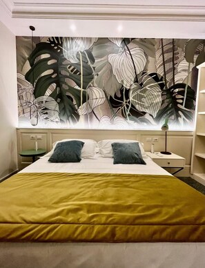 A hotel room with a bed, two pillows, a nightstand, a lamp, and a wall with a leaf pattern. - Hotel Bellonda (Forte dei Marmi)