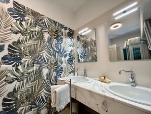 A bathroom with two sinks, a large mirror, and a wall with a tropical leaf pattern. - Hotel Bellonda (Forte dei Marmi)