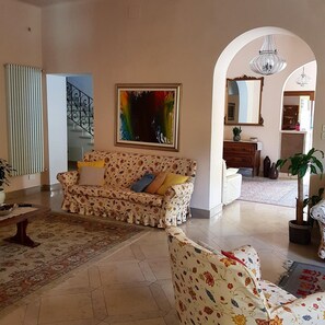 A living room with a sofa, a coffee table, a rug, a painting, and a staircase. - Hotel Bellonda (Forte dei Marmi)