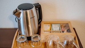 Uma bandeja com uma chaleira elétrica Philips, duas taças de vidro transparentes e duas canecas de vidro transparentes.