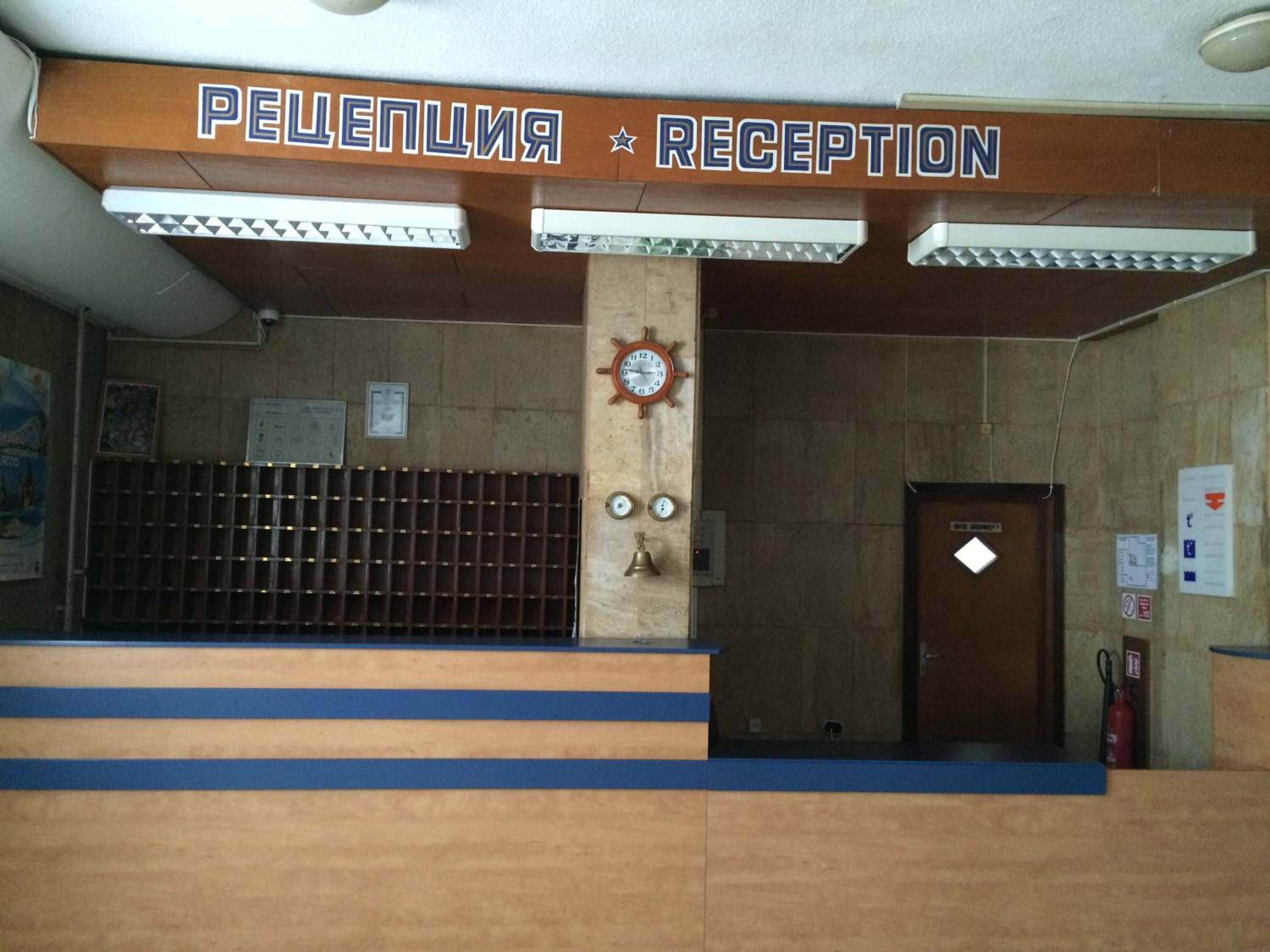 A reception area with a sign reading 'PELEPENIA RECEPTION' and a clock on the wall.