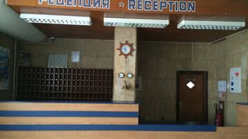 Una zona de recepción con un cartel que dice 'PELEPENIA RECEPTION' y un reloj en la pared.