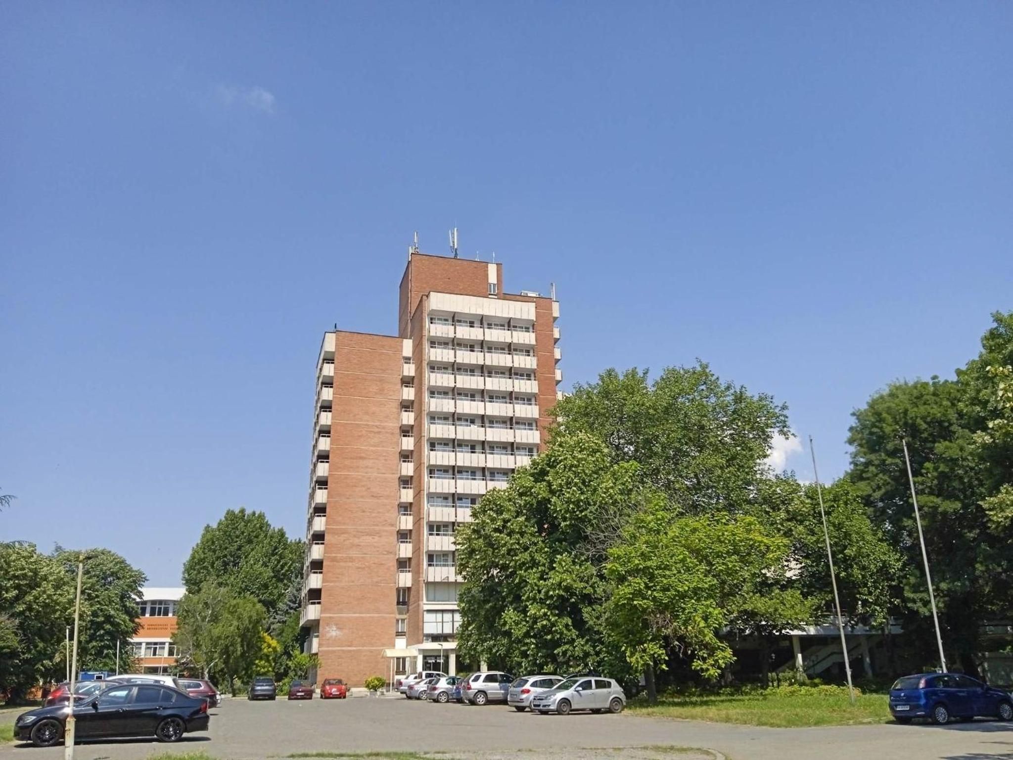 Een meerhoog gebouw met een parkeerplaats ervoor.