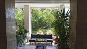Un espacio de estar al aire libre cubierto con un sofá y una mesa, rodeado de plantas en macetas.