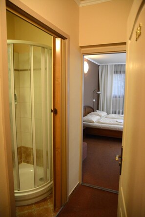 A hotel room with a shower, a bed, and a mirror reflecting the room. - Hotel Minerva (Mosonmagyarovar)