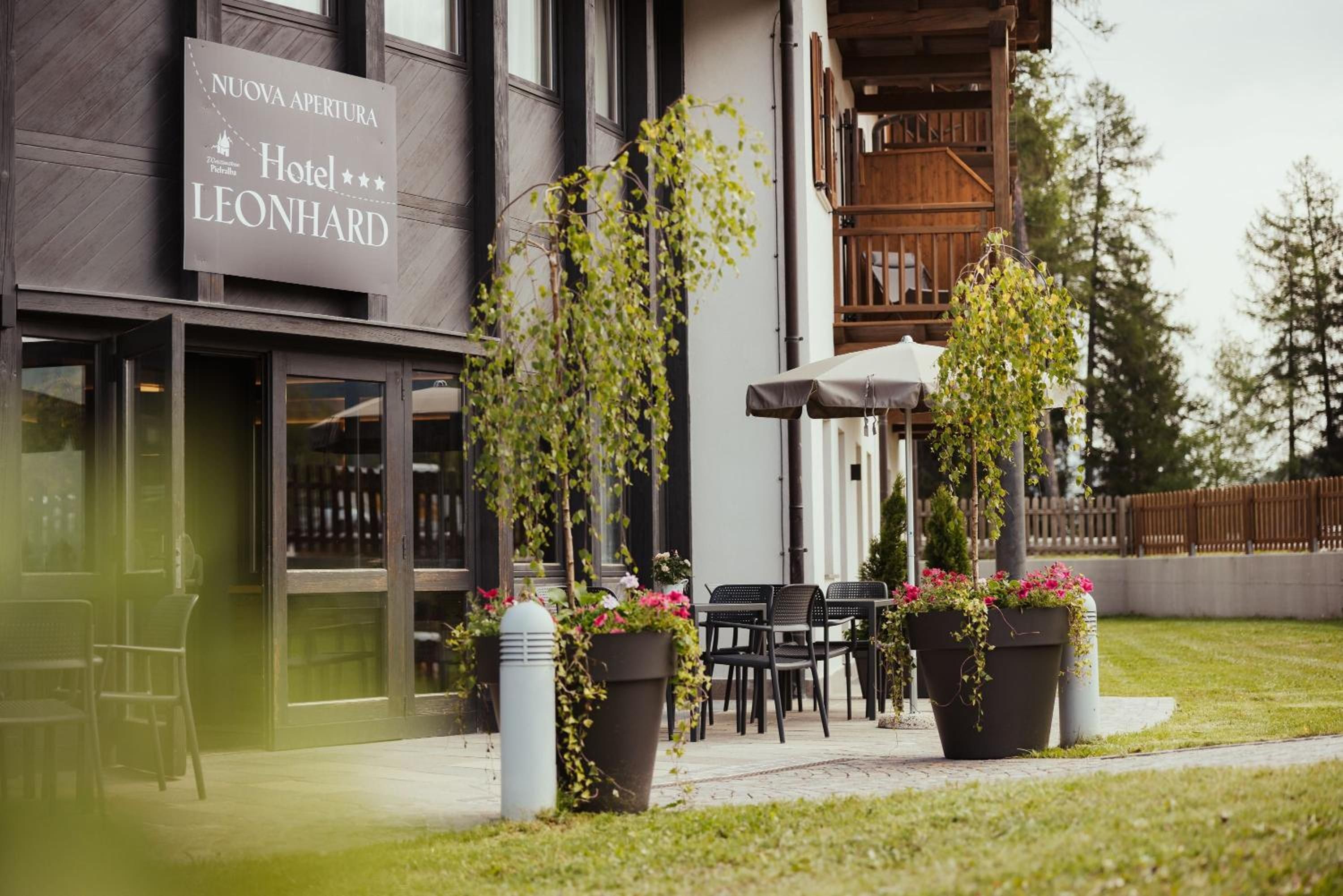 A hotel entrance with a sign, outdoor seating, and potted plants.