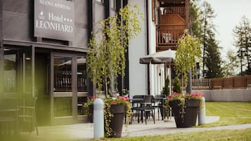 Ingresso di un hotel con insegna, posti a sedere all'aperto e piante in vaso.