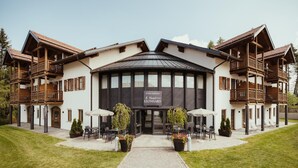 A hotel with a central entrance, multiple balconies, and outdoor seating areas. - Hotel Leonard (Nova Ponente)