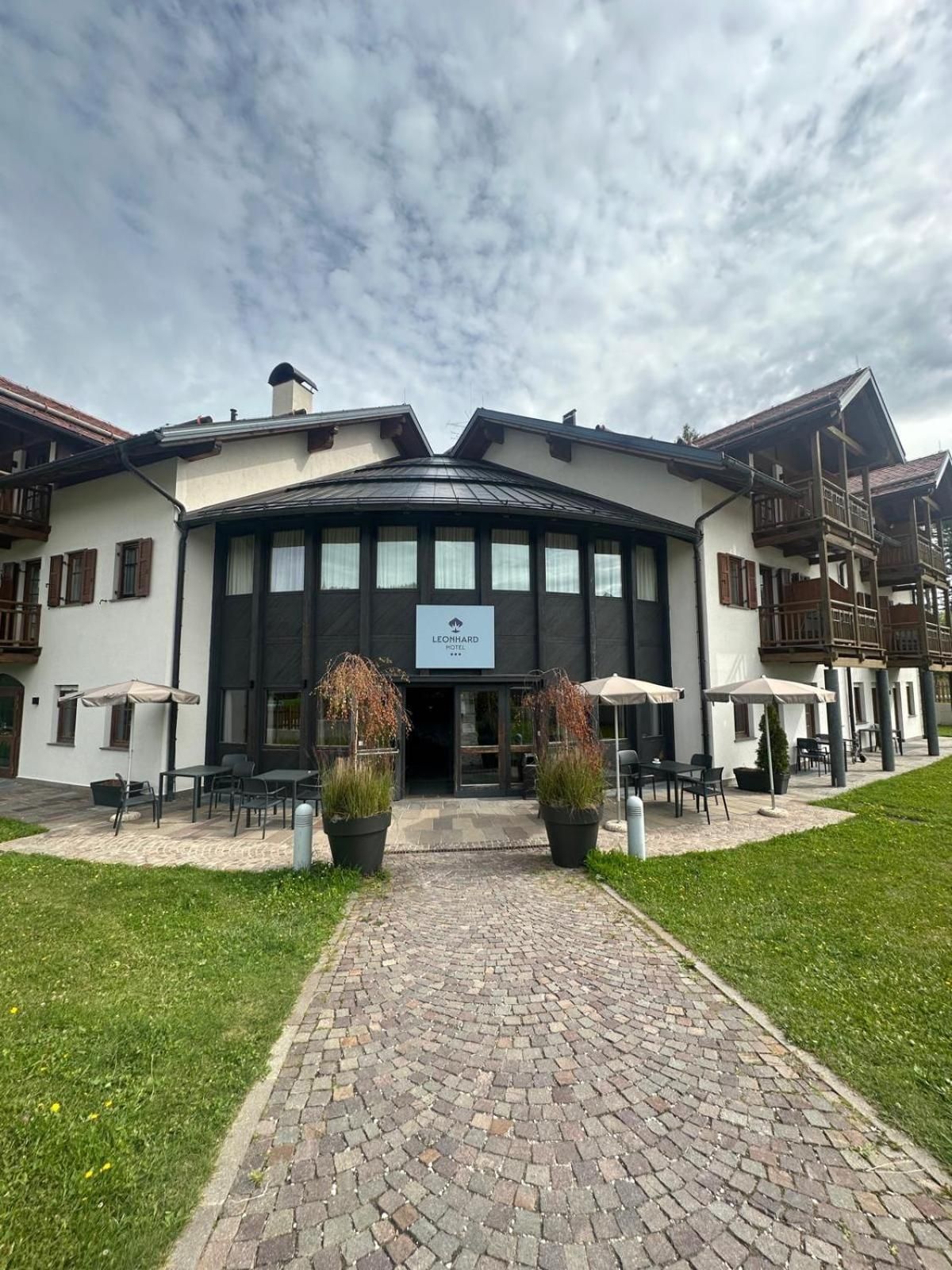 A hotel with a central entrance, outdoor seating, and a paved walkway leading to the entrance.