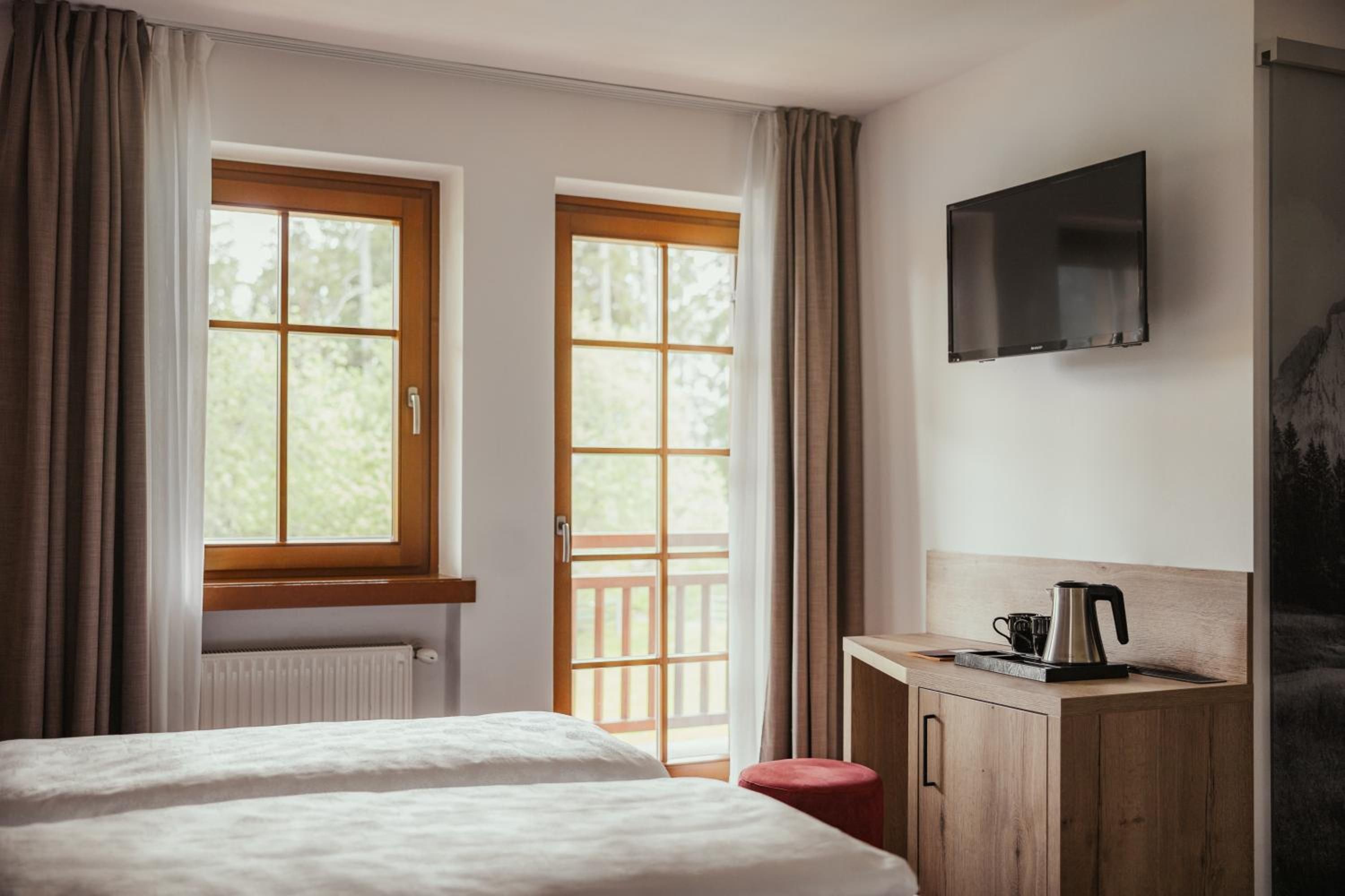 Una camera d'albergo con due letti, una scrivania con un bollitore e una TV a parete.
