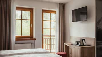 Una camera d'albergo con due letti, una scrivania con un bollitore e una TV a parete.