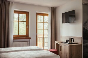 Habitación de hotel con dos camas, un escritorio con hervidor y televisión en la pared.