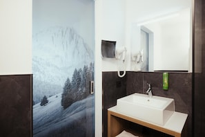 A bathroom with a large mirror, a white sink, and a towel rack. - Hotel Leonard (Nova Ponente)
