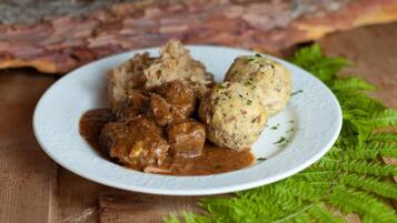 Ein Teller mit Hackbällchen und Soße, ein Holztisch und ein Farn.