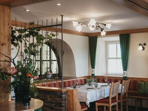 A cozy dining area with a stone wall, wooden bench seating, and a table set for two. - Hotel Muhr (Poellauberg)