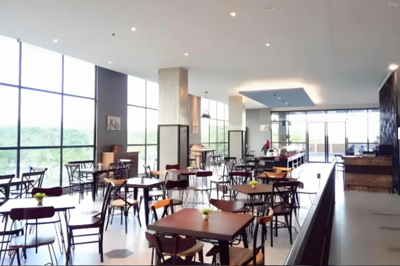 Un vaste espace dédié à la salle à manger, avec de nombreuses tables et chaises, de grandes fenêtres et un plafond haut.