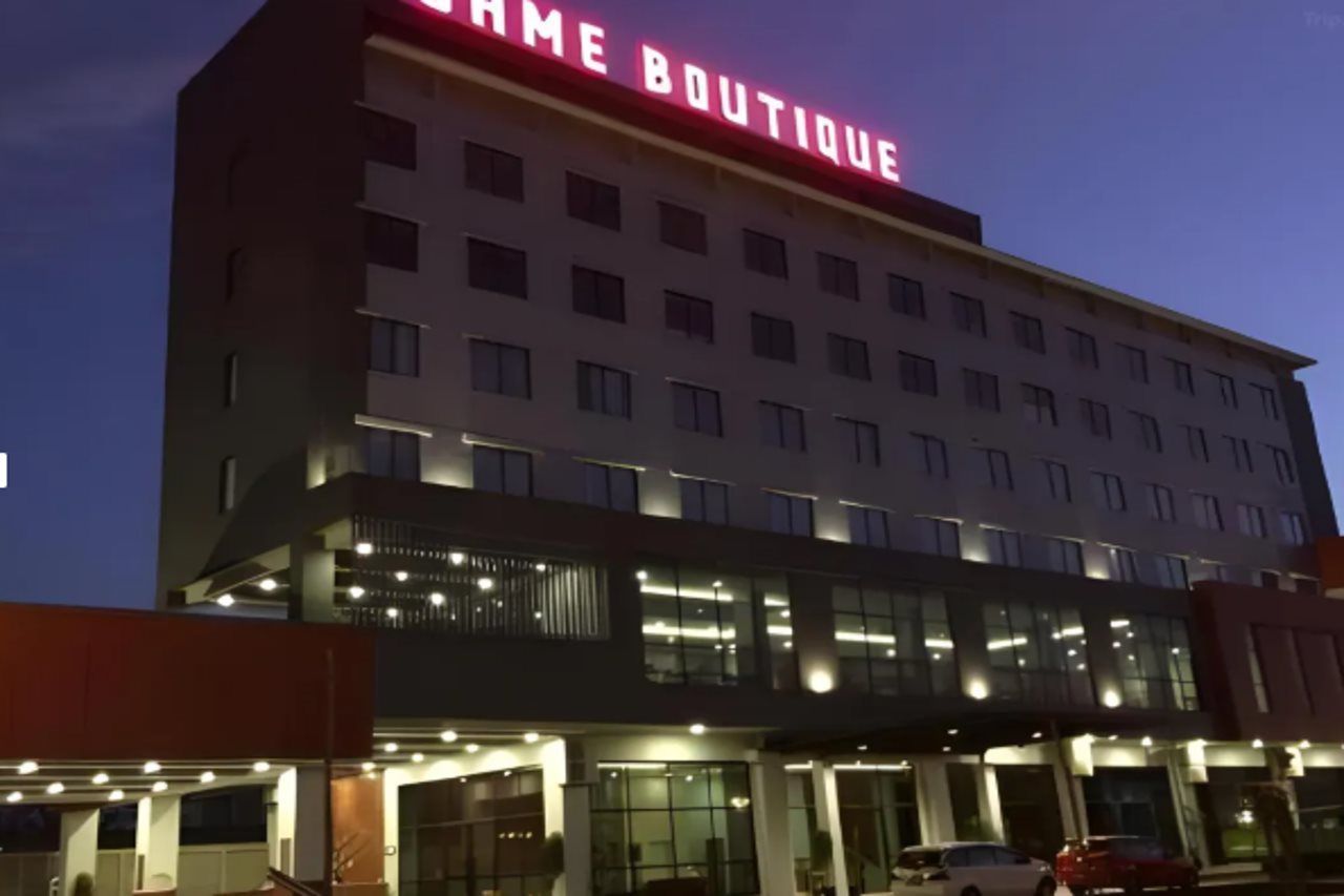 Un immeuble à plusieurs étages, sur lequel on peut voir une enseigne bien visible indiquant « NAME BOUTIQUE » au sommet.