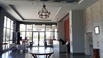 Un hall d’entrée spacieux avec une table centrale, un espace salon et un comptoir d’accueil.