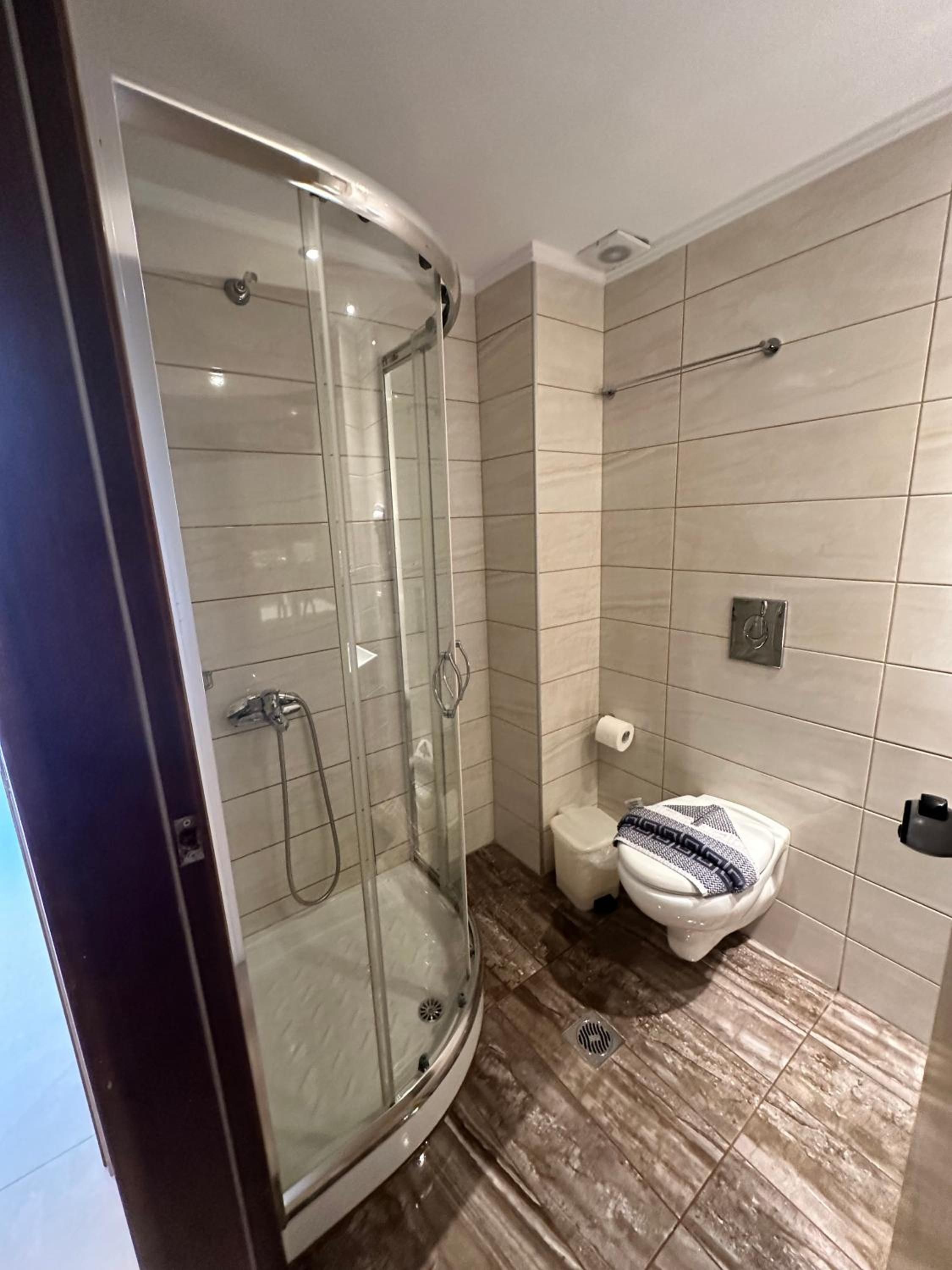 A modern bathroom with a glass-enclosed shower, a toilet, and a sink.