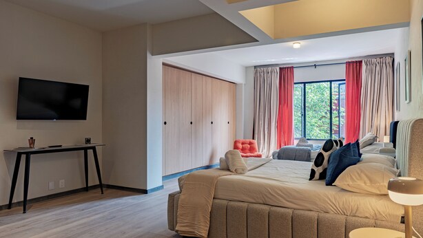 A modern bedroom with a bed, a TV, a desk, and a window with curtains. - Incredible Loft in Centro walk to Zócalo (Mexico City)
