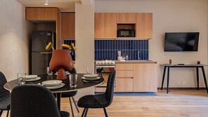 A modern kitchen with a refrigerator, stove, microwave, and a dining area with a table and chairs. - Incredible Loft in Centro walk to Zócalo (Mexico City)