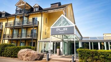 Un hôtel avec une enseigne indiquant « PUR HOTEL » et une entrée moderne en verre.