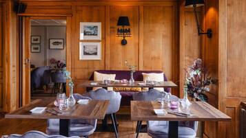 Un restaurant aux murs en bois, avec un canapé et des tables dressées pour le repas.