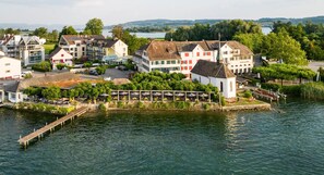 A riverside property with a dock, buildings with red shutters, and a small white structure. - Rossli Hurden (Freienbach)