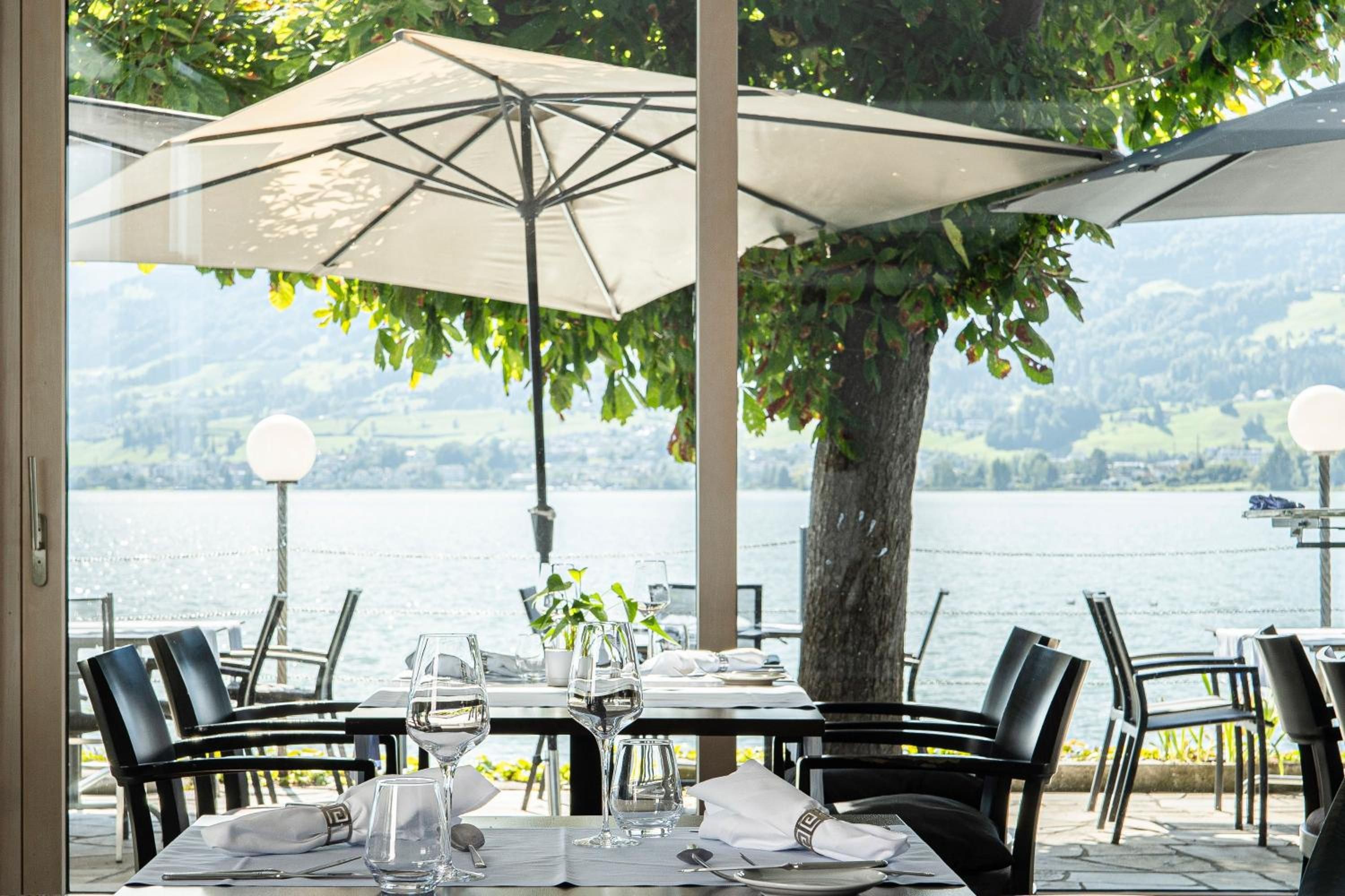 An outdoor dining area with a table set for two, overlooking a lake.