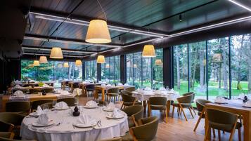 A restaurant with round tables, chairs, and hanging lamps.