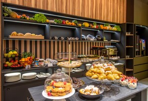 Un bufé con diversos alimentos, como frutas, pasteles y postres.