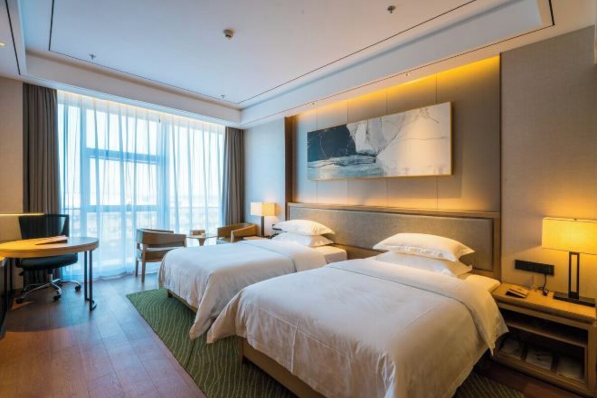 A hotel room with two beds, a desk, and a chair.