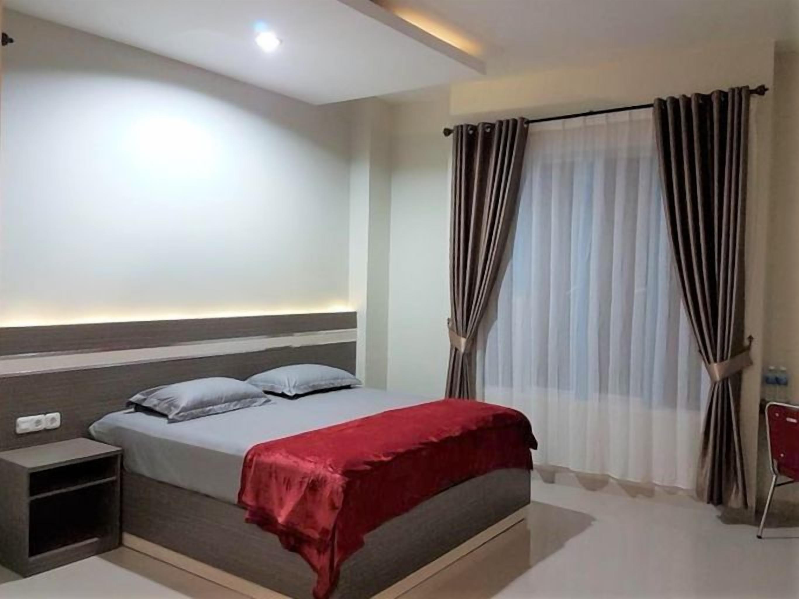 A bedroom with a bed, bedside table, and curtains.