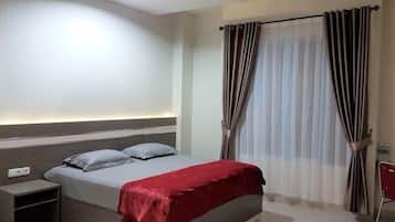 A bedroom with a bed, bedside table, and curtains.