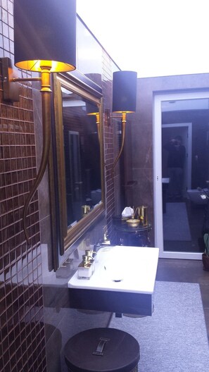 A bathroom with a large mirror, a white sink, and two wall-mounted lamps. - Noclegi Gwardia (Koszalin)