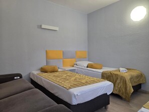 A hotel room with two beds, a sofa, and a small table. - Noclegi Gwardia (Koszalin)