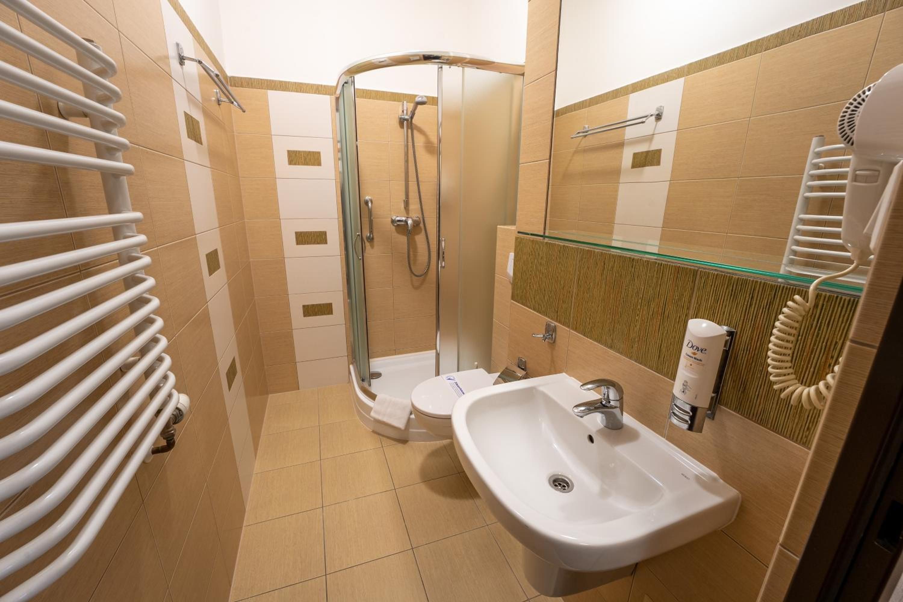 A bathroom with a glass shower enclosure, a white sink, and a towel rack.