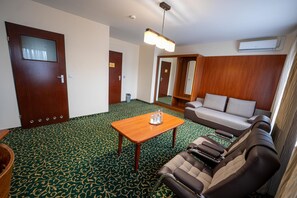 A hotel room with a green patterned carpet, a wooden table with a tray, a sofa, and a mirror. - Hotel Szelcow (Lesko)