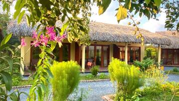 A building with a thatched roof, surrounded by a garden with various plants and a gravel pathway.