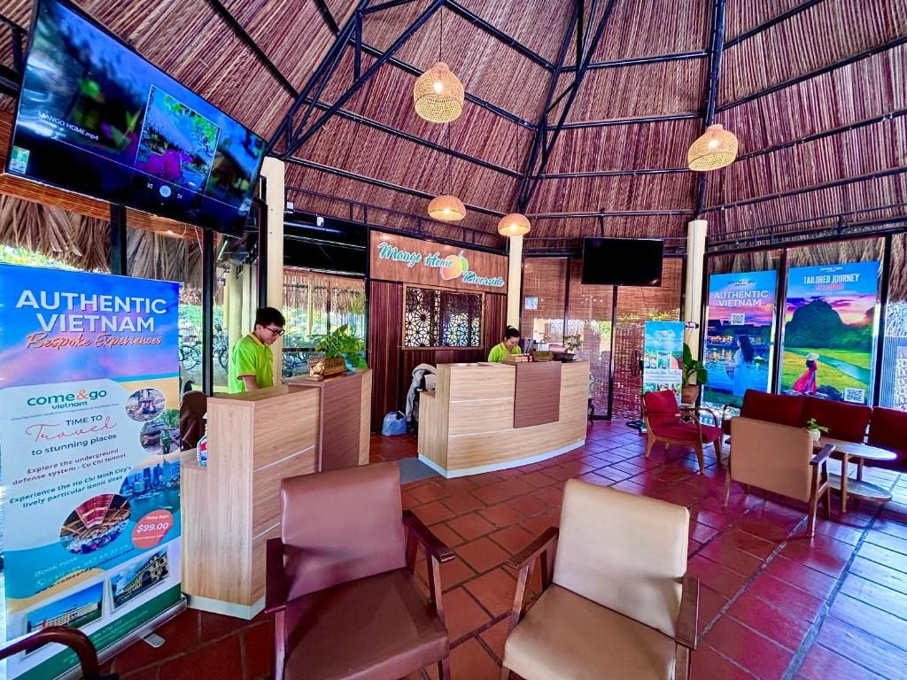 A reception area with a wooden reception desk, seating area with chairs, and a large TV screen displaying images.