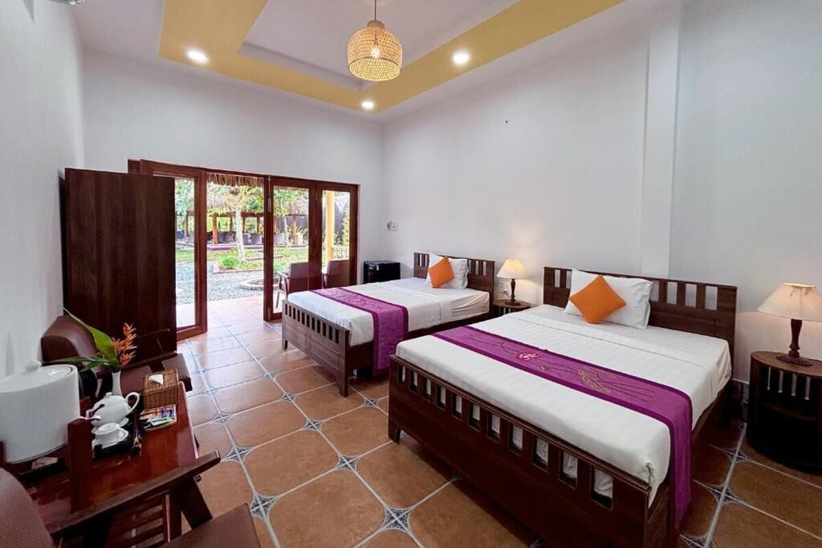 A hotel room with two beds, a desk, a chair, and a window.