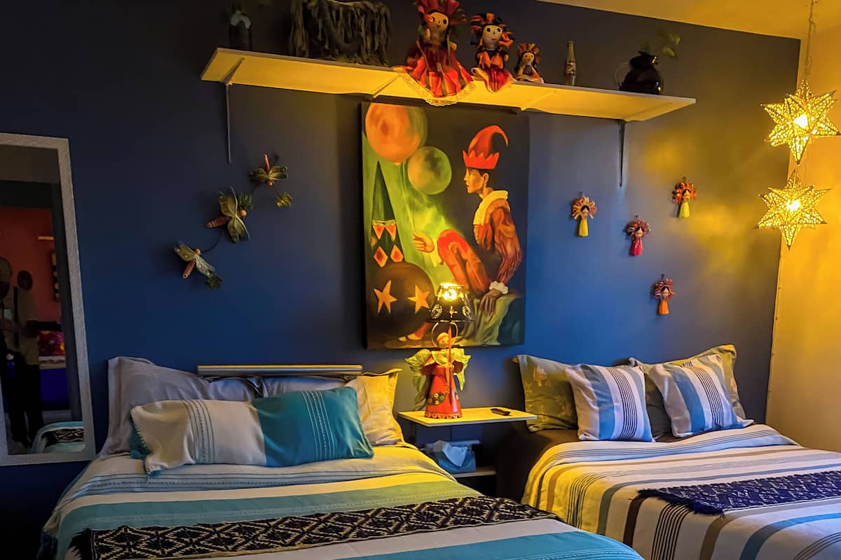 Ein Schlafzimmer mit zwei Betten, einem Nachttisch, einem Spiegel, einem Bild und Wanddekorationen.