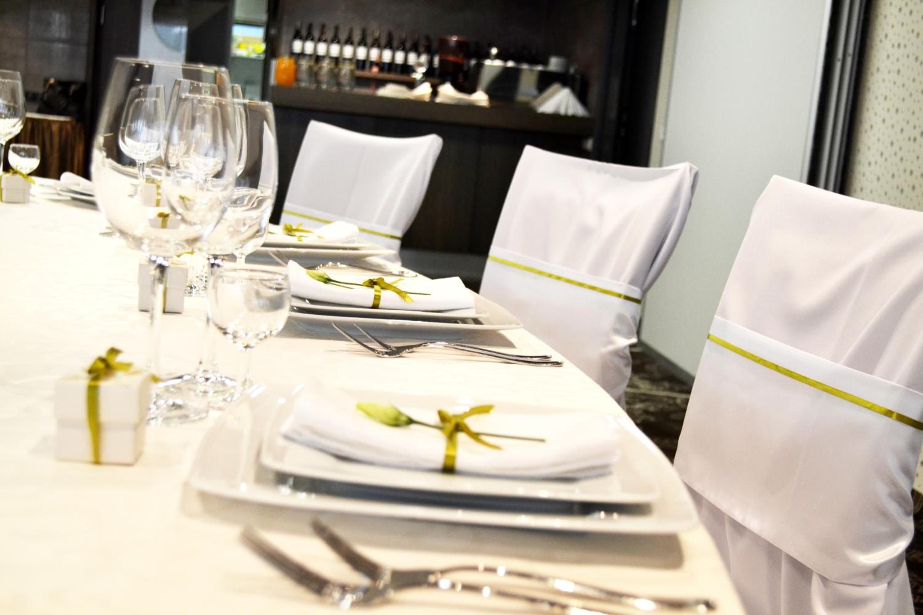 A table set for a formal dining experience with white tablecloths, neatly arranged plates, cutlery, and glasses.