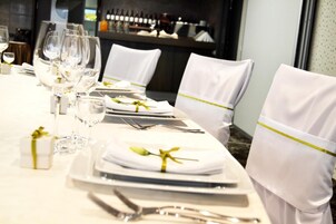 Een gedekte tafel voor een formeel diner, met witte tafellinnen, netjes gerangschikte borden, bestek en glazen.