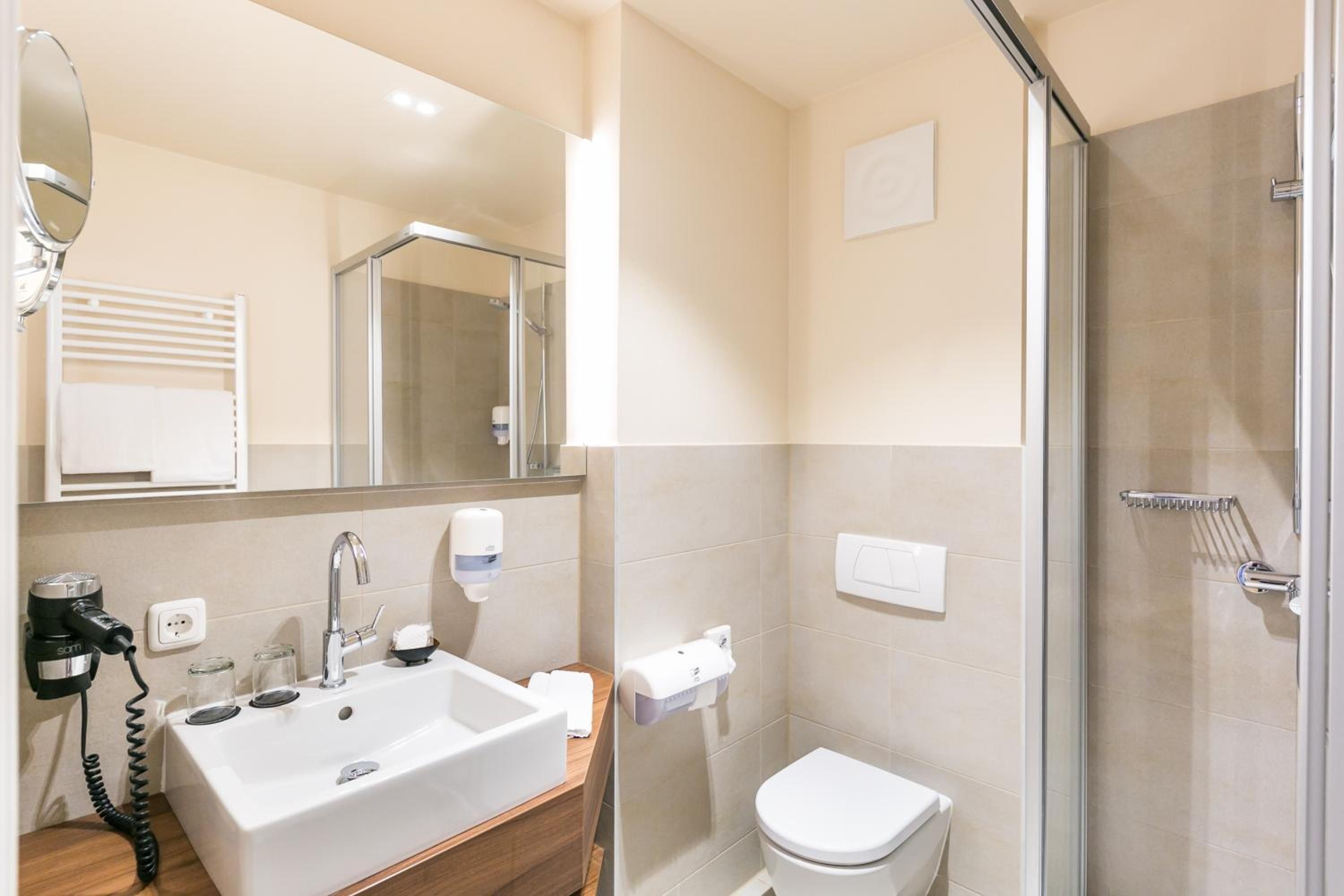 Ein Badezimmer mit Waschbecken, Spiegel, Toilette und Dusche.