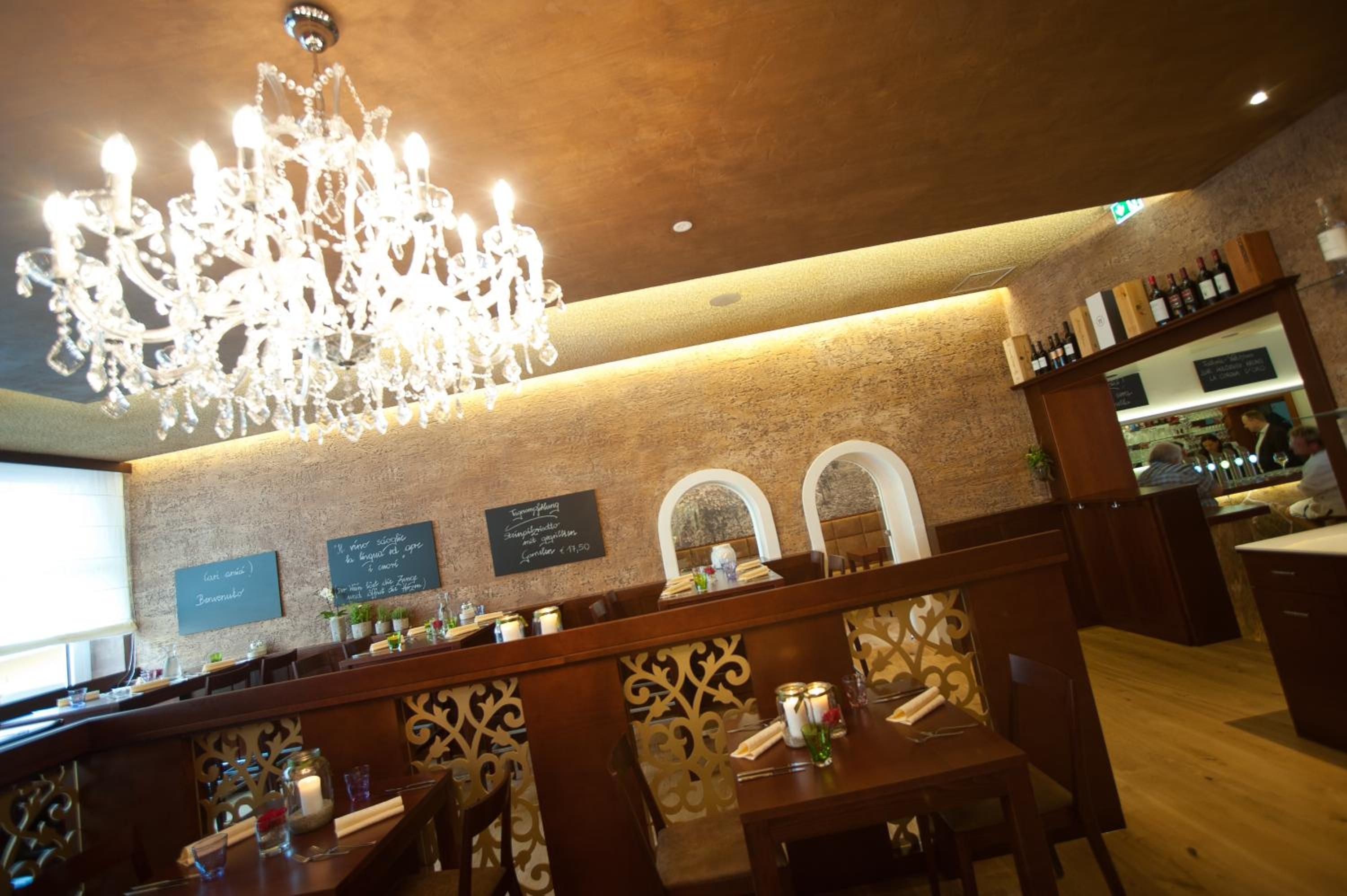 Ein Restaurantinneres mit einer Kronleuchter, Holztischen und einer Bar.