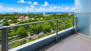A balcony with a metal railing overlooking a cityscape with greenery, a Ferris wheel, and a body of water. - Luxury Stay for Less • Cozy Vibes + Epic Sunsets (Pasay City)