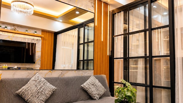 A modern living room with a sofa, TV, and a potted plant. - Luxury Stay for Less • Cozy Vibes + Epic Sunsets (Pasay City)