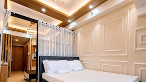 A modern hotel room with a large bed, a chandelier, and a mirror. - Luxury Stay for Less • Cozy Vibes + Epic Sunsets (Pasay City)